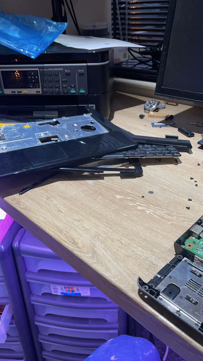 A laptop stripped down on a workbench with its keyboard and base removed